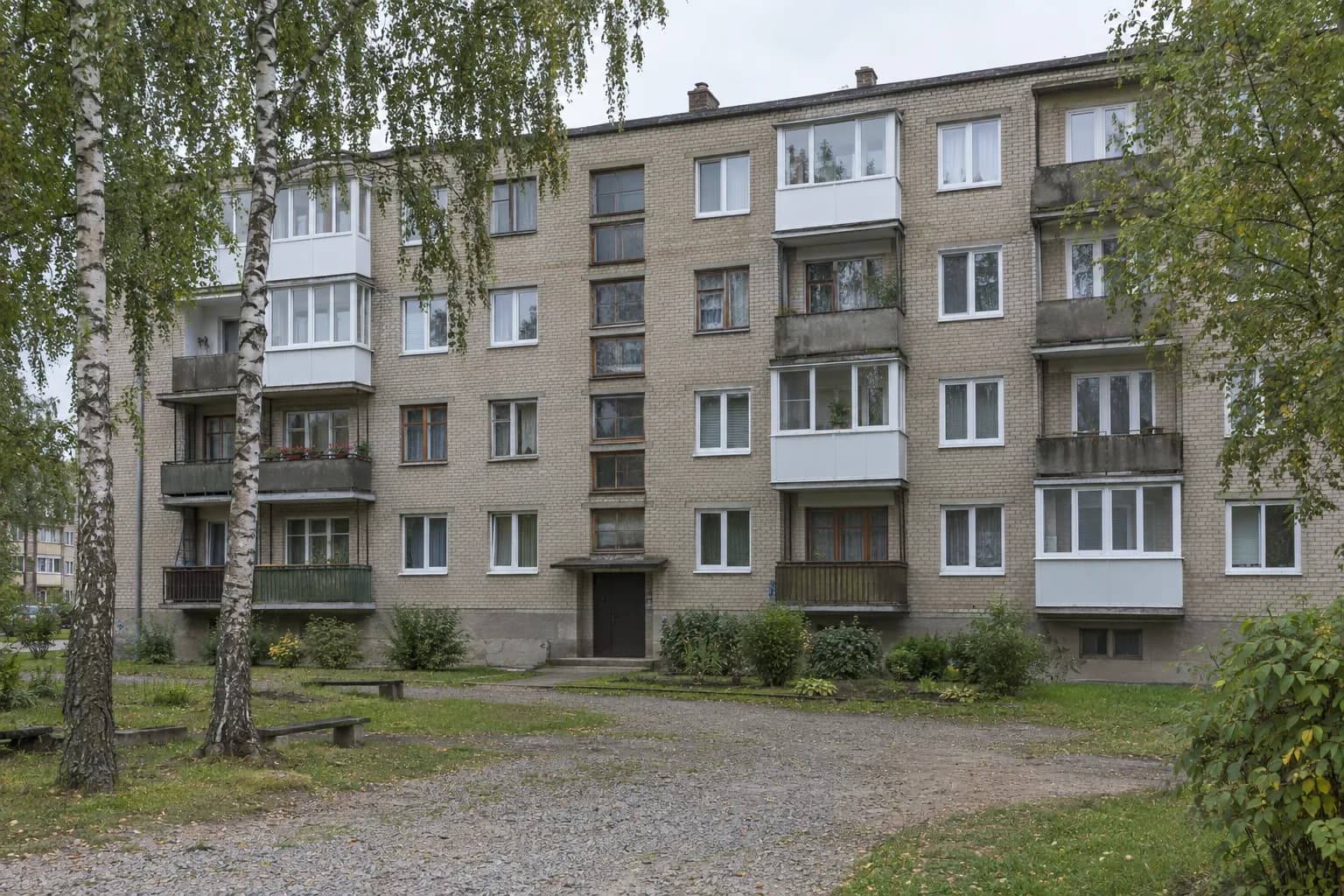 Sovietmečio plytų daugiabutis Lietuvoje: dalis balkonų įstiklinti baltais PVC rėmais, dalyje butų nauji balti langai